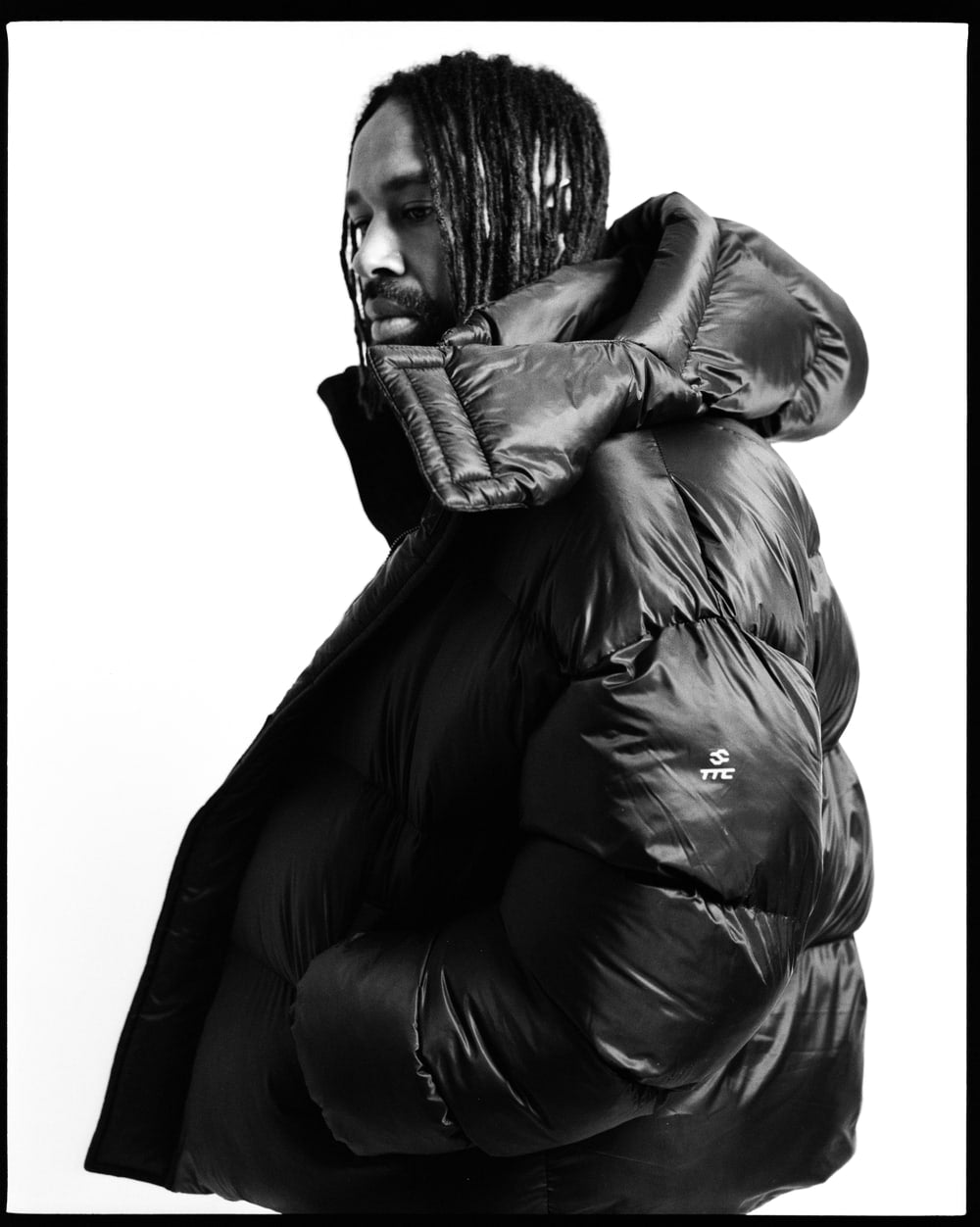 Side portrait showing the volume and hood of the black Puffer Jacket