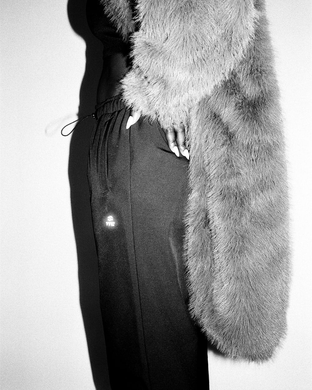 OG Trackpants worn with a textured coat, showing the waist adjustment and reflective logo